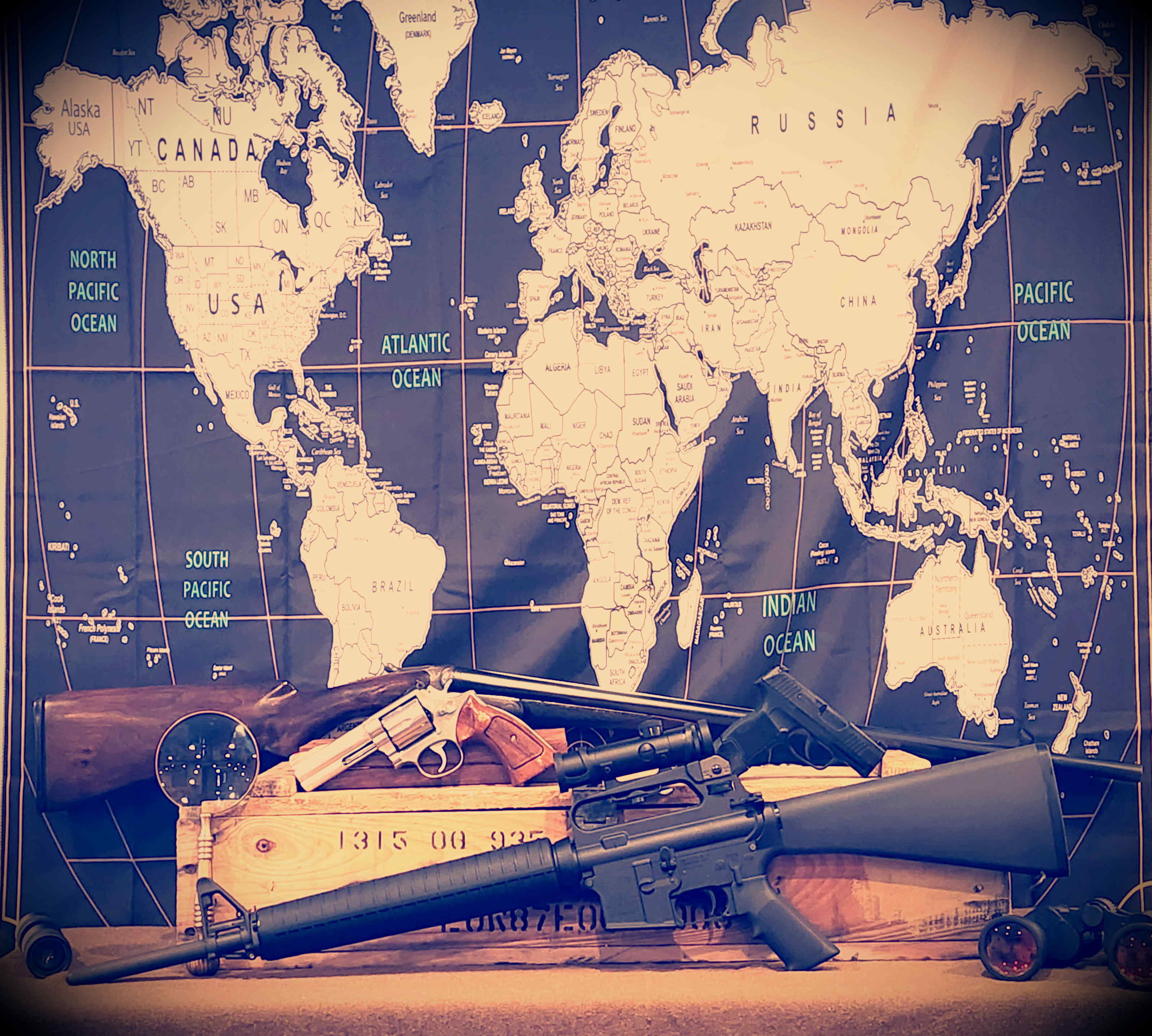World map behind a display of historic and modern firearms.